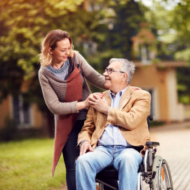 senior man on wheelchair accompanied by his wife